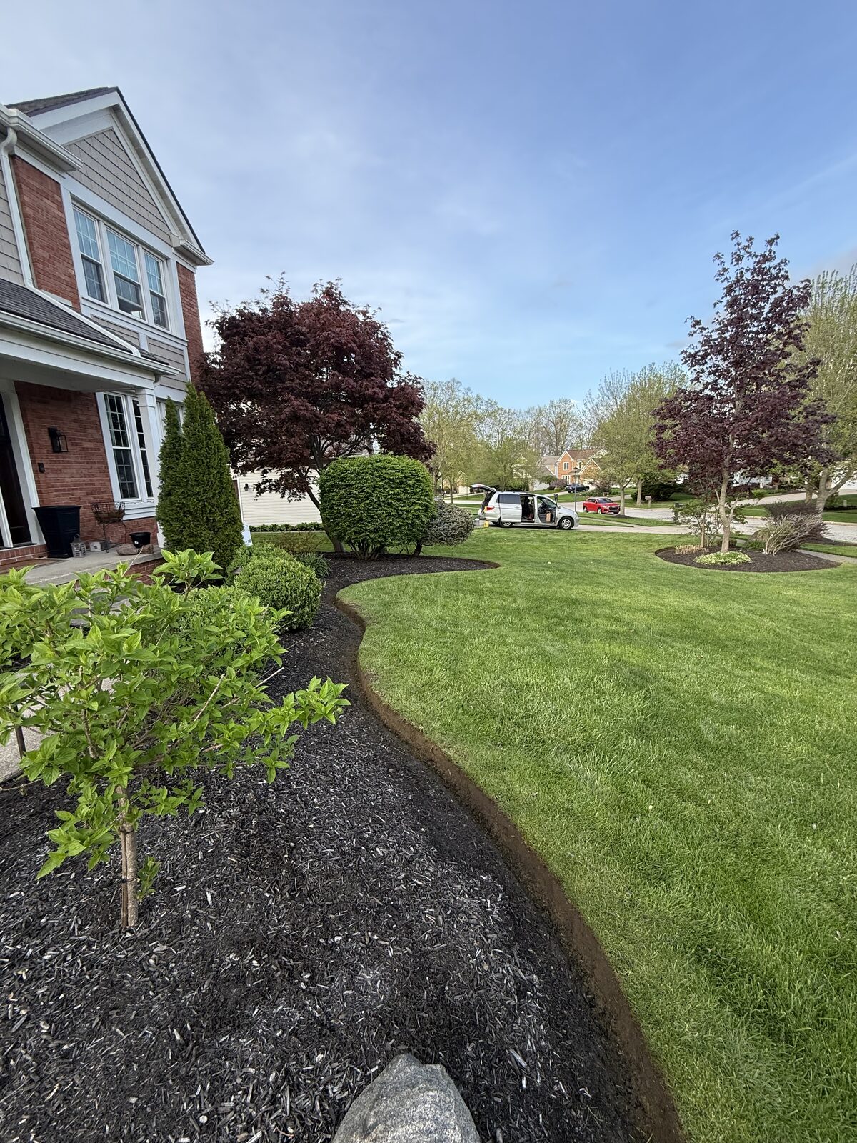 Crisp hand-cut shovel edge separating a mulched bed from the green lawn